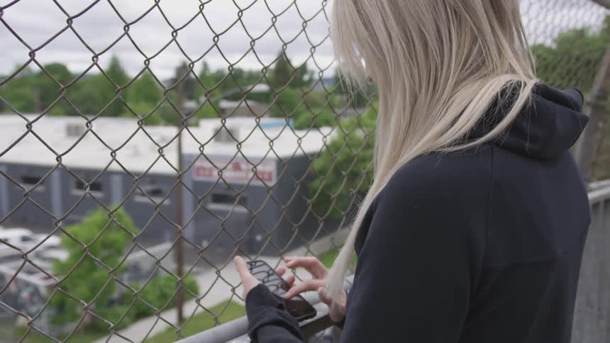 A woman standing next to a gate touching her smartphone
