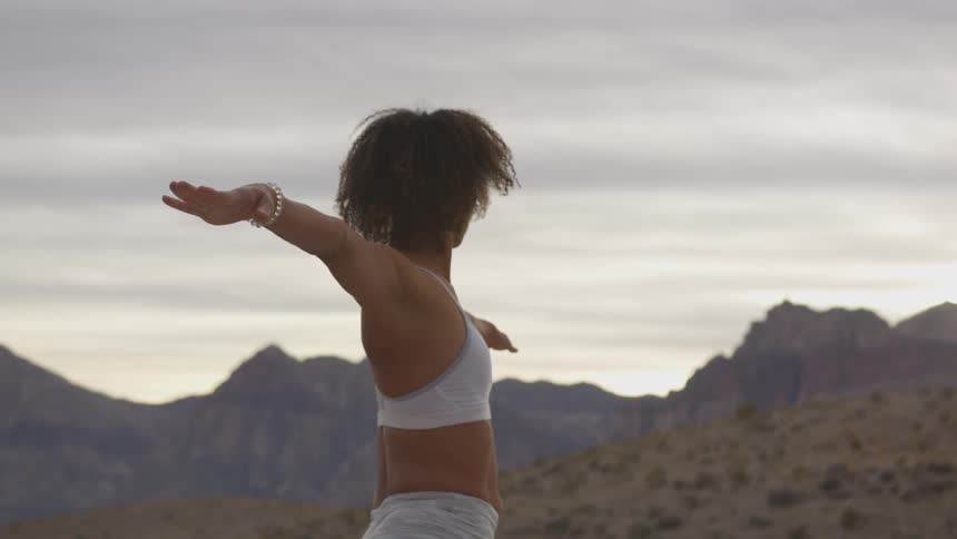 Woman doing yoga on a desert at sunset
