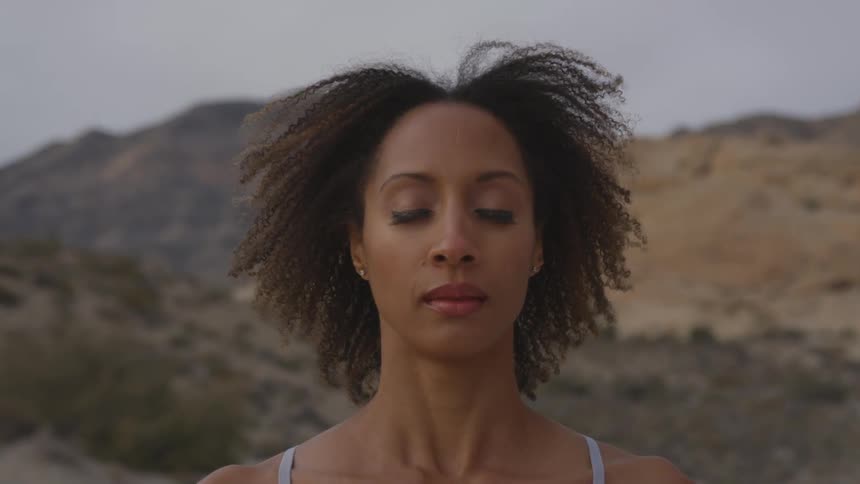 A young woman sits with her eyes closed