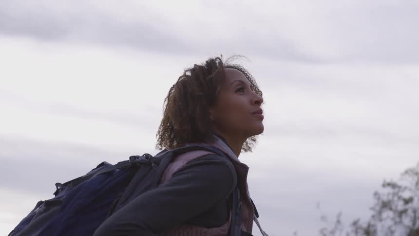 A female hiker walking outdoors on a cloudy day