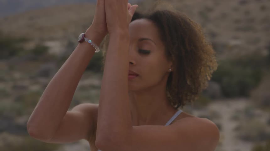 A black woman practices yoga in the desert
