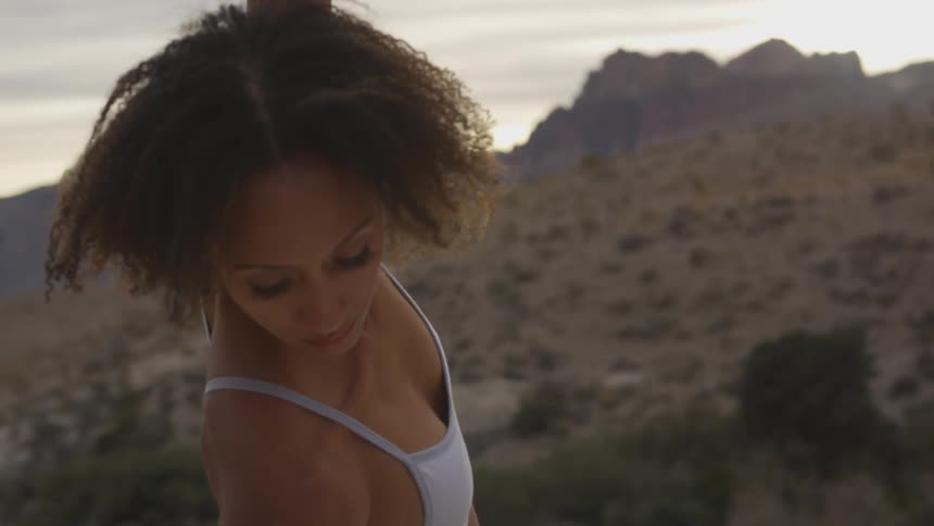 A woman stretches with a backdrop of the arid landscape