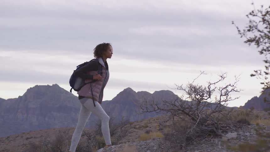 A woman hikes up a rocky hillside