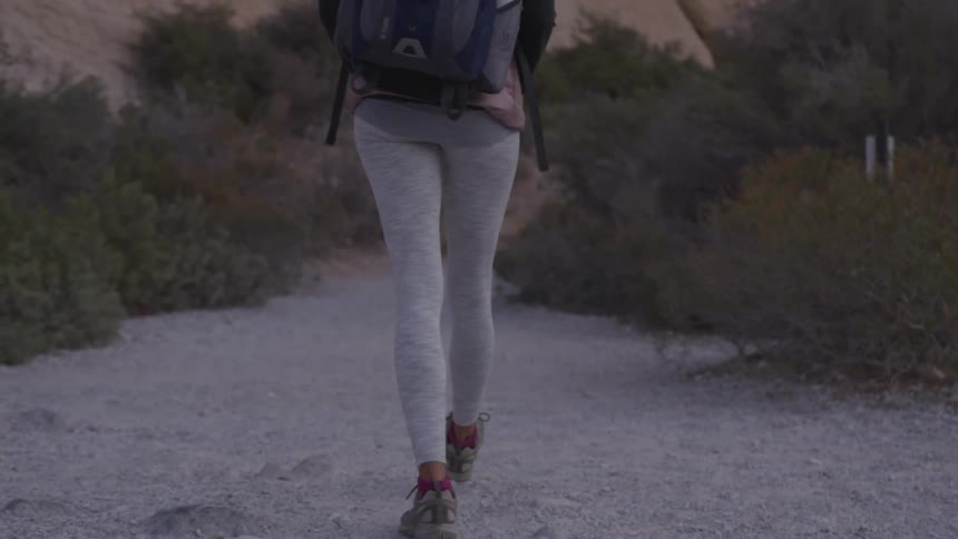 A woman in yoga pants hikes on a rocky path