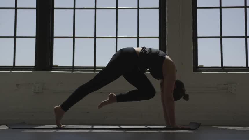 A woman stretches a leg high in the air as shes leaning down