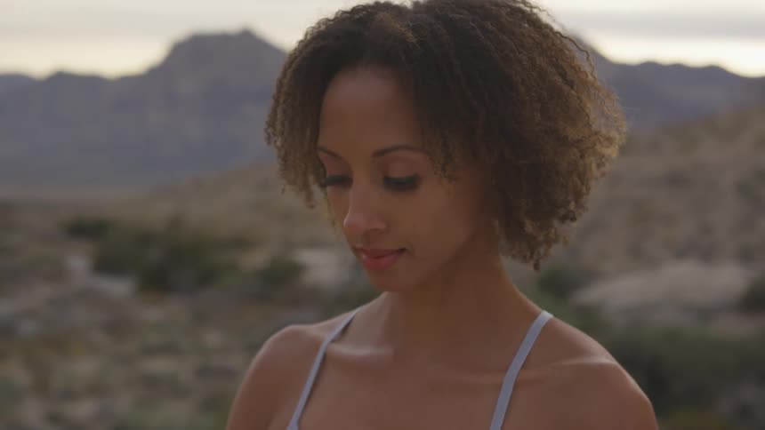 A woman standing in mountainous plains is looking down