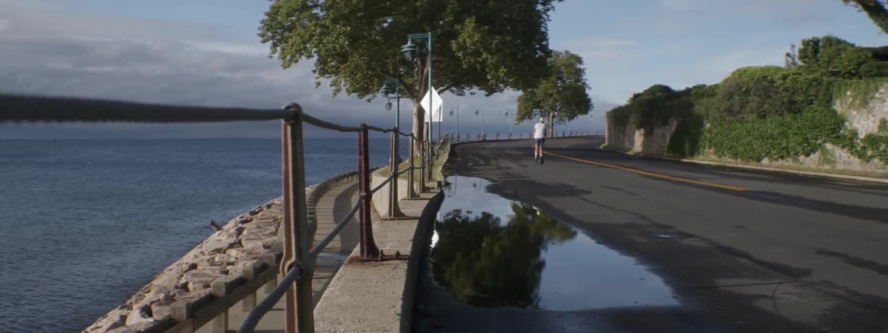 A person rollerblades down an oceanside road