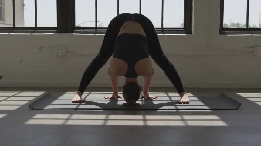 A woman leans on her head in a yoga pose