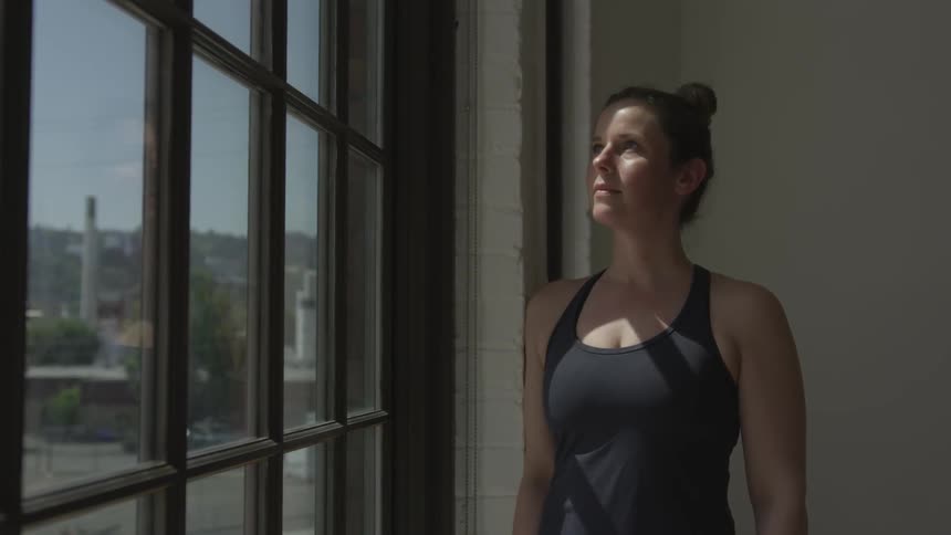 A white woman stares out of a window