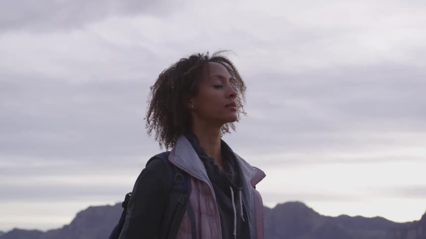 Woman standing still meditating on a desert at sunset