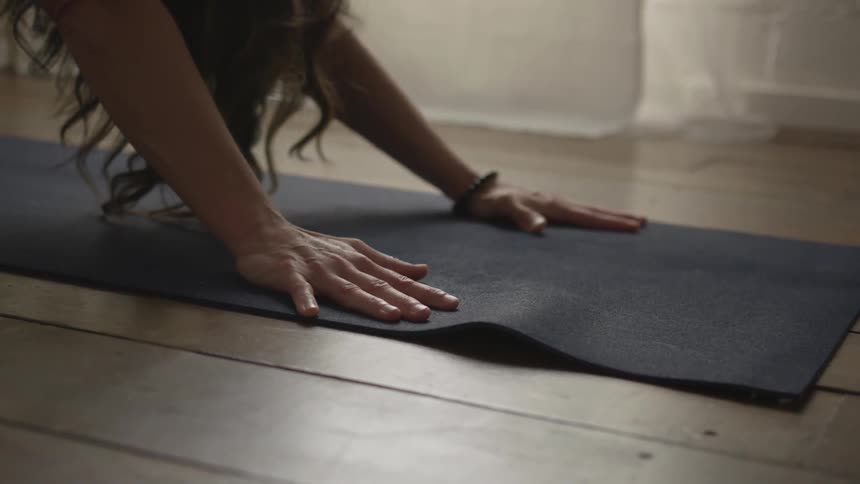A woman inside stretching on a mat on the floor