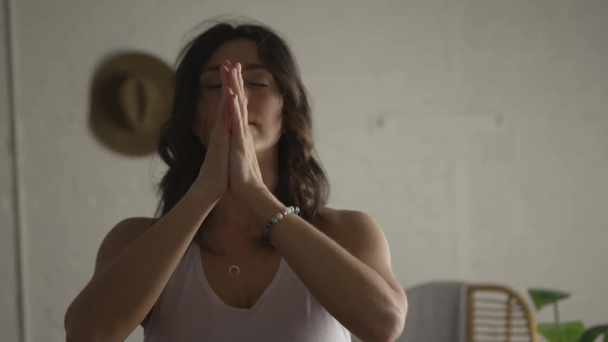 A woman meditates and does yoga indoors
