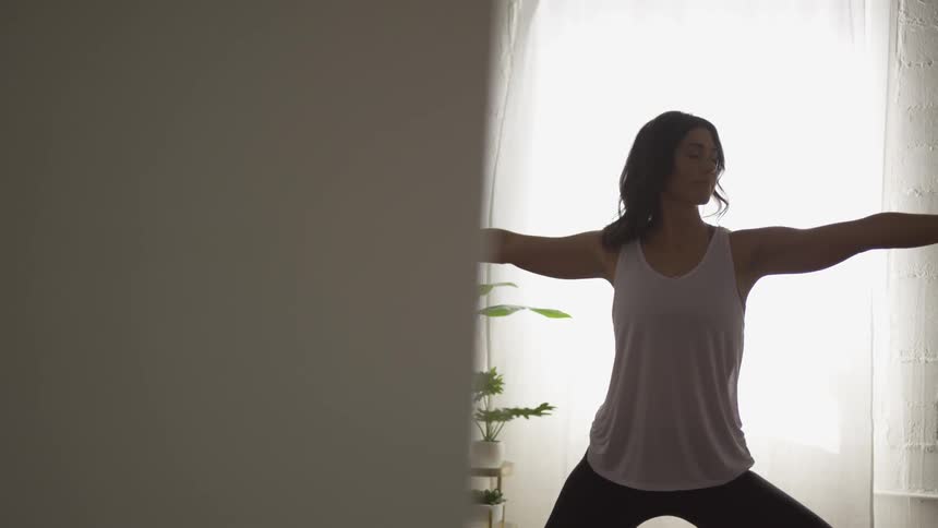 A woman performing yoga in a white walled room