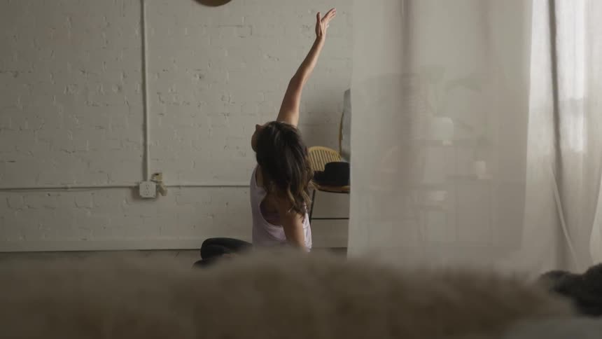 A woman stretches and raises her right arm