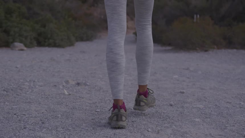 A woman walks along a gravel pathway