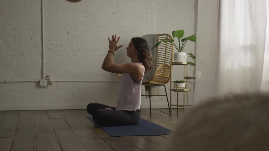 A woman does yoga and raises and lowers her arms