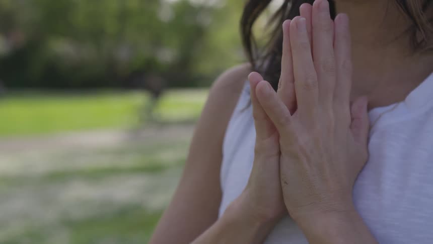 A woman meditates and does yoga outside in a park