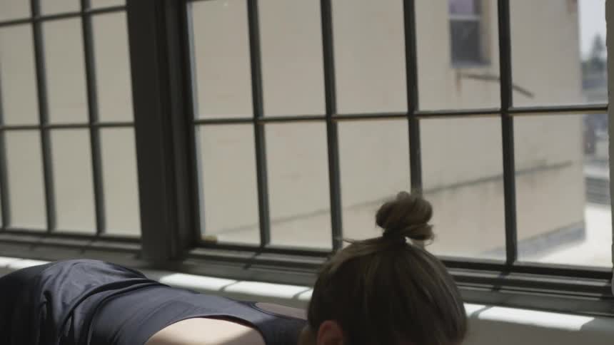 A woman stretches in front of a window