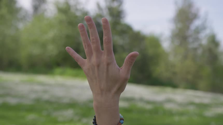 A white woman holds her spread hand up in the air