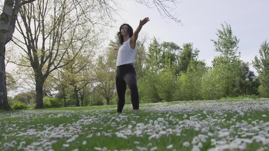 A woman does yoga in a field of seeding dandelions