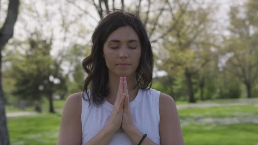 A woman with clasped hands in a meditation pose
