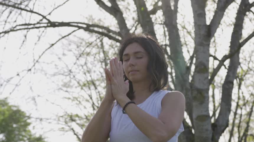 A young woman is meditating outdoors on a cloudy day