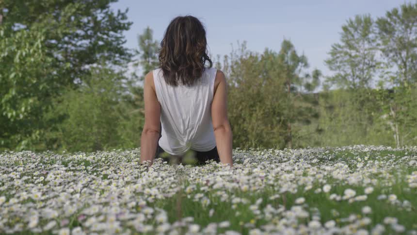 Woman sitting on a grass field with flowers