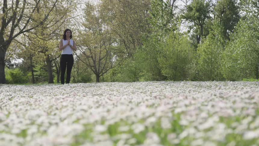 A young woman prays in a field of flowers