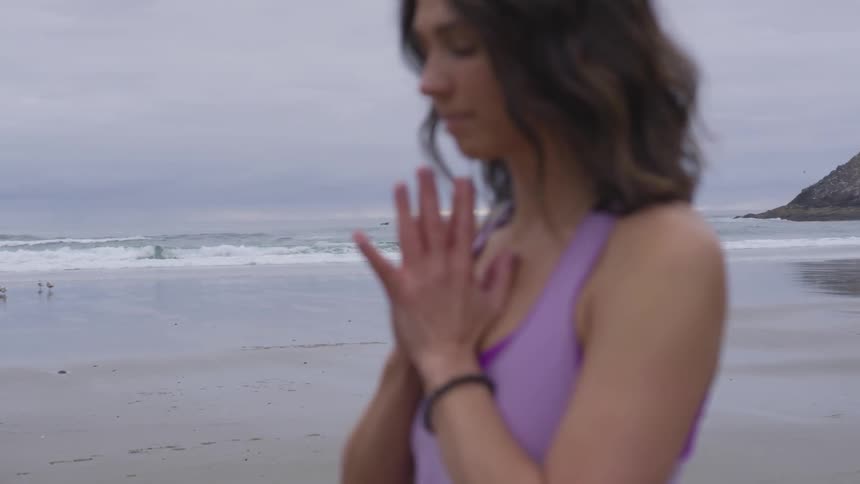 Woman practicing yoga on the sand of a beach