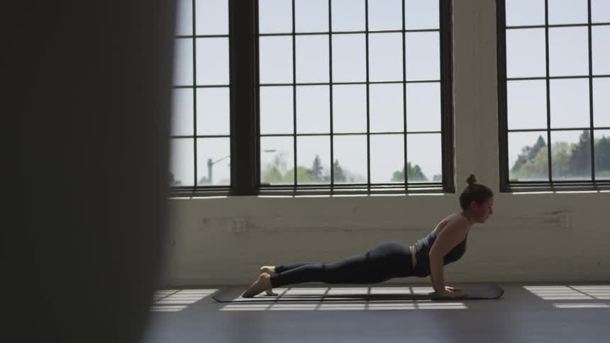 A woman does yoga stretches on a mat