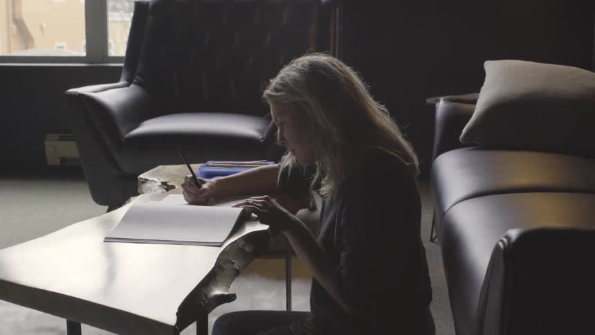 Woman sitting on the floor of a living room writing on a notepad