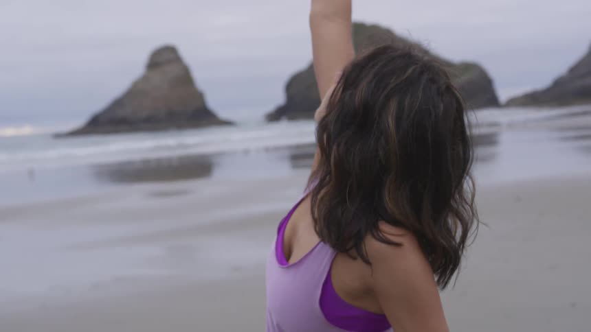 A young woman does yoga on the beach
