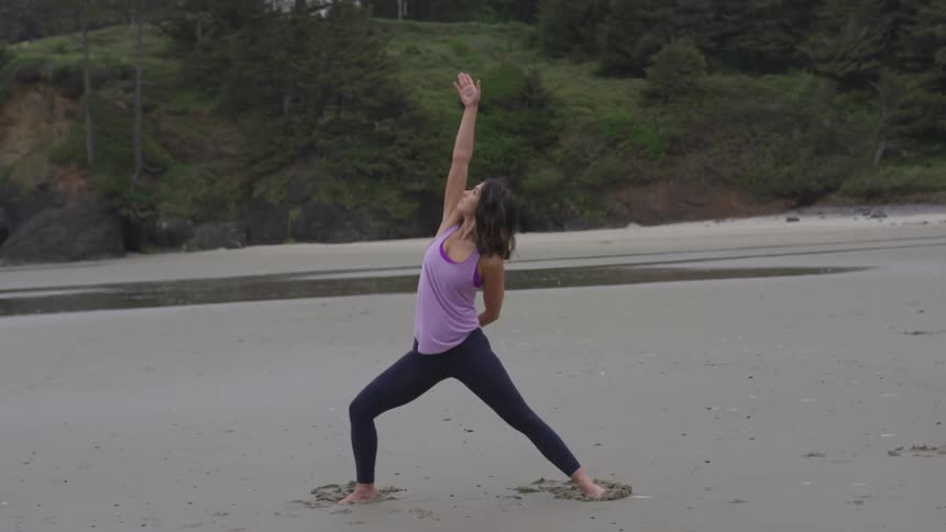 Woman doing yoga in the sand on a beach barefoot