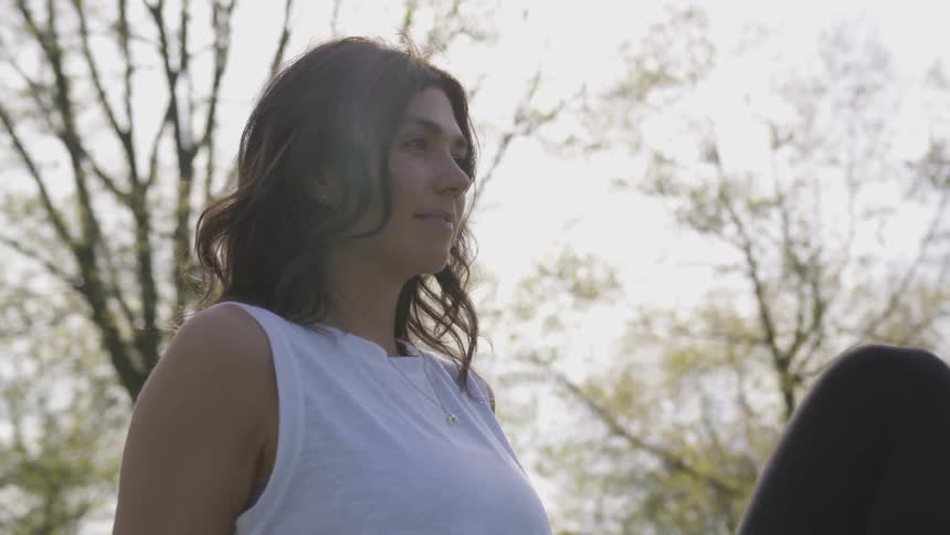 A woman sits around near trees
