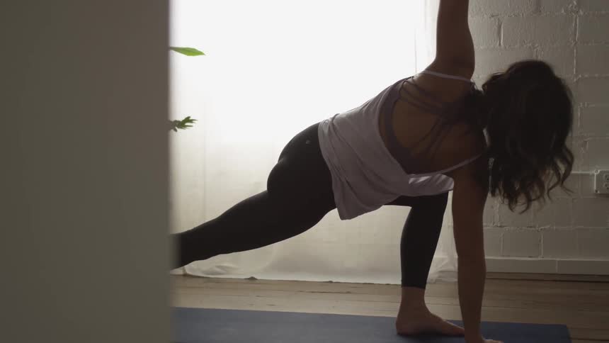 A woman does a yoga pose indoors