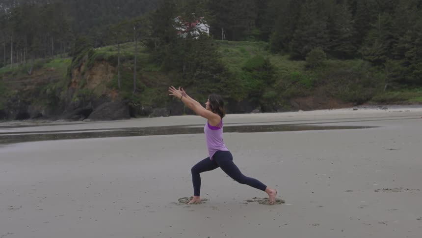 Woman practicing yoga on the sands of a beach