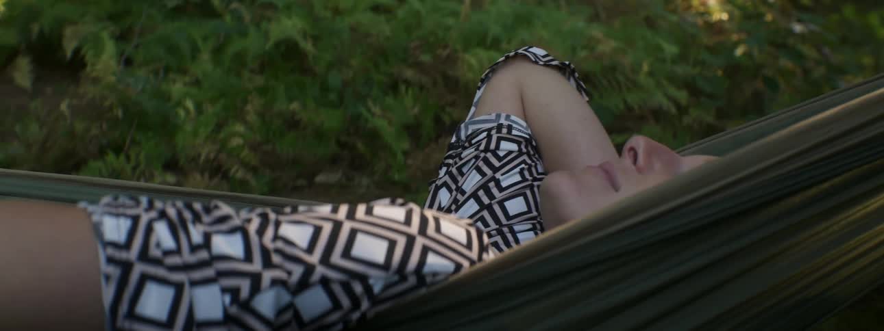 A woman lays in a hammock swaying back and forth