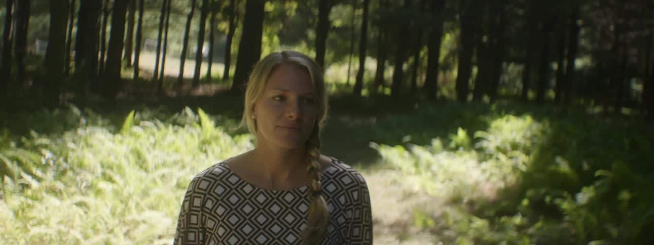Woman smiles as she walks through the woods