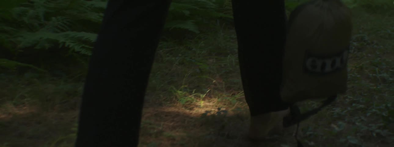 A view of someone walking barefoot and carrying a bag