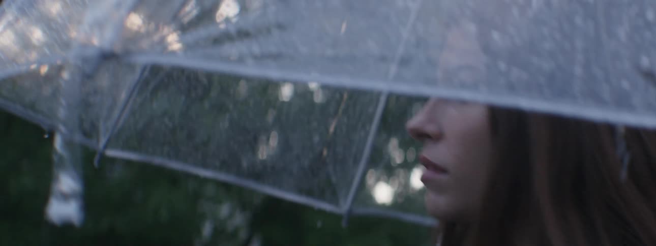 A woman walking in the rain under a clear umbrella