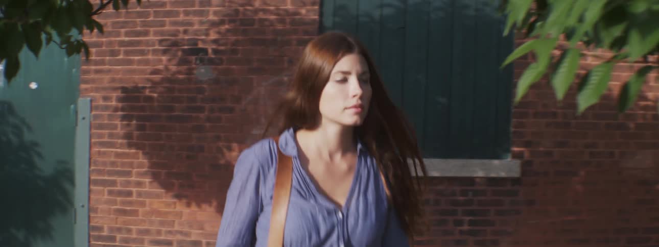 Woman walks down a sidewalk next to a red brick building