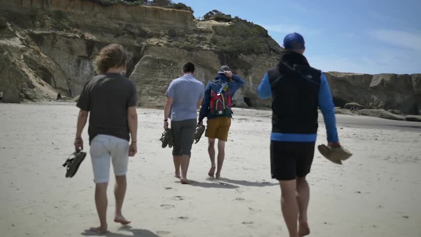 Group of young men walking along a sunny beach