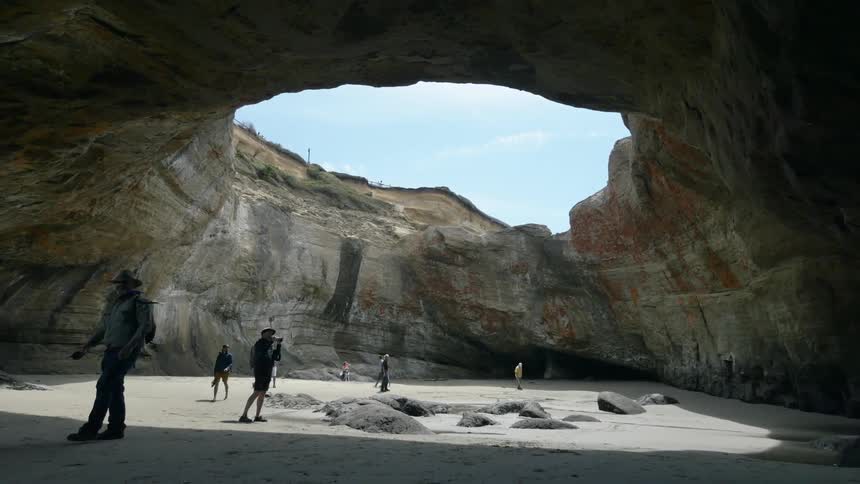 Photographers exploring a cave with a natural skylight