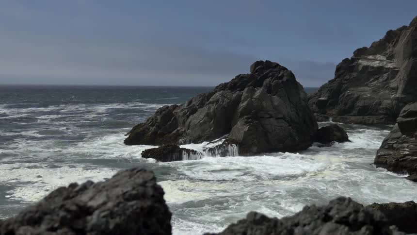 Waves crash against large rocks in the ocean