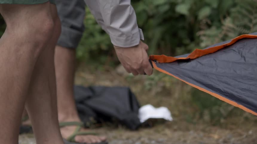 Two men are pitching a tent at a campsite