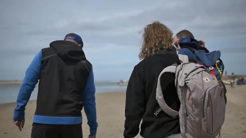 Group of men with packs walking along a beach