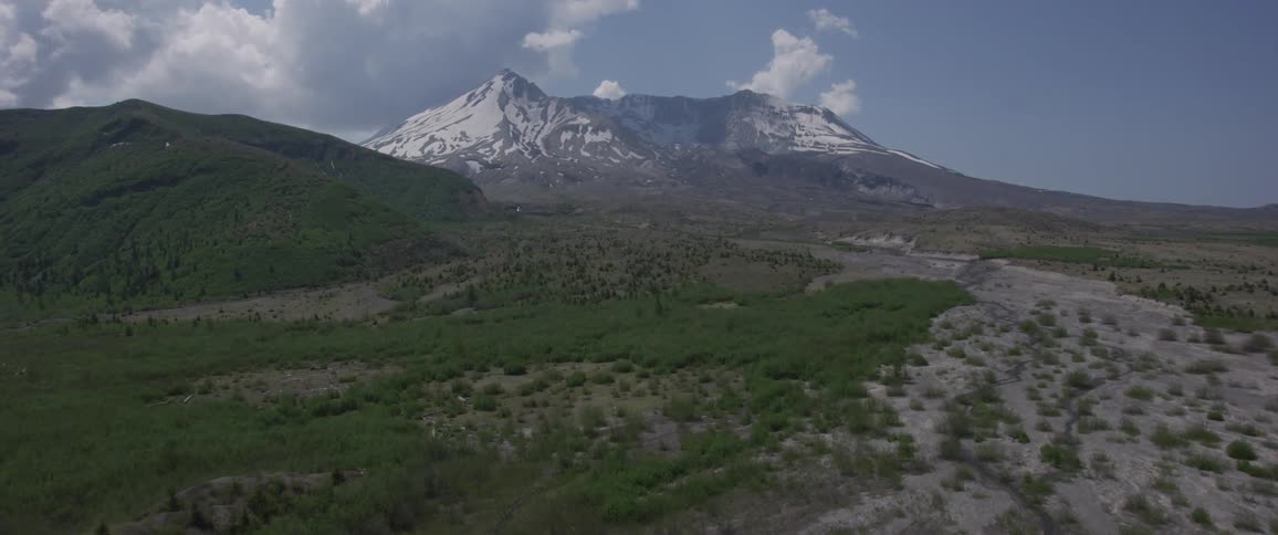 The camera flies over a lake towards a mountain