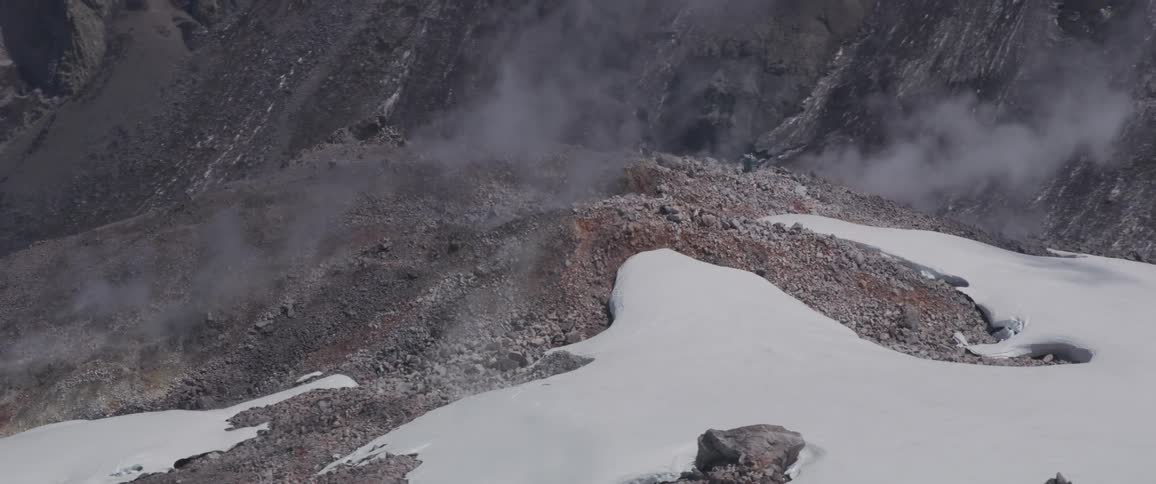 Mountains covered in snow with steam arising from the top
