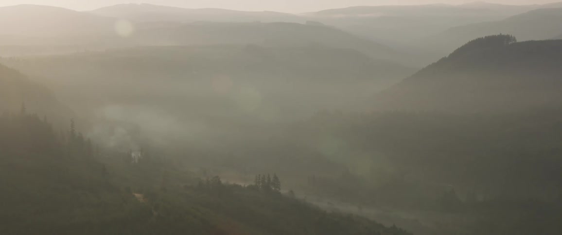 The camera flies over foggy hills