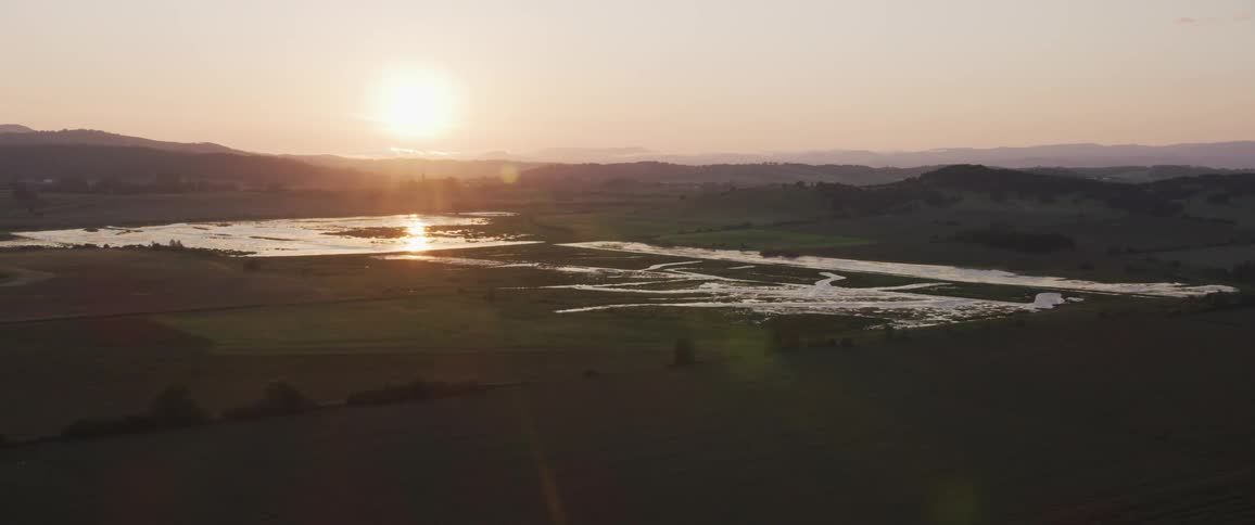 The camera flies near a body of water between hills